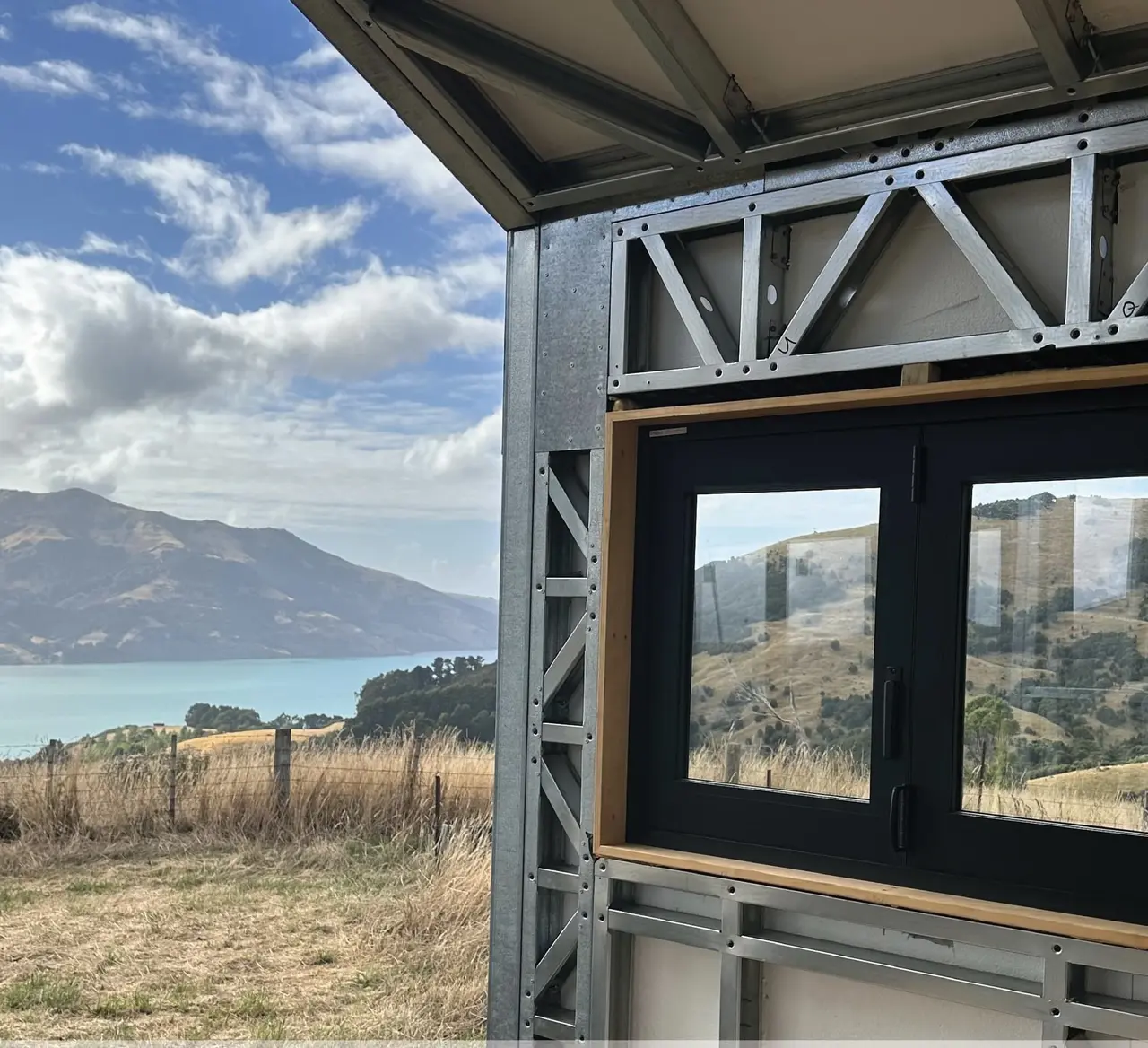 Light steel frame wall with a window opening looking out over water and hills